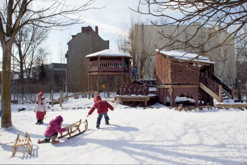 Kinder spielen an einem 'Wintertag im Schnee auf dem Spielplatz