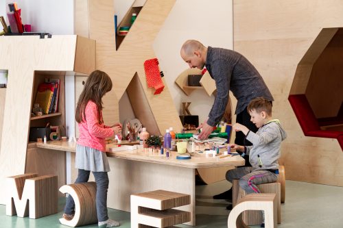 Ein Erzieher bastelt mit Kindern 3D-Buchstaben