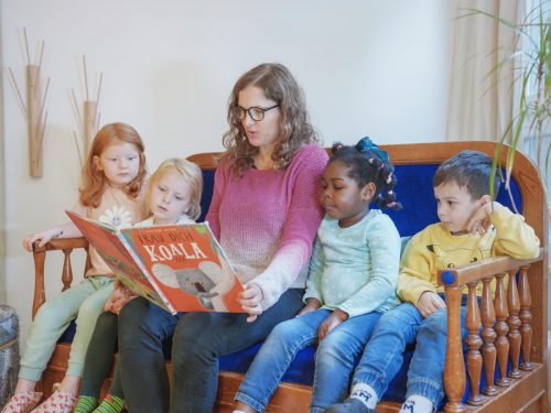 Eine Pädagogin liest Kindern aus einem Buch vor