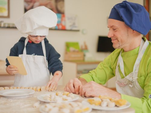 Ein Koch in der Kita bäckt mit einem Kind Brötchen