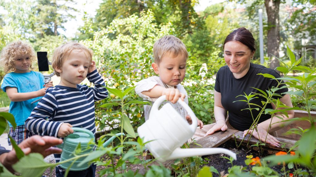 Eine Erzieherin mit Kindern im Gemüsebeet