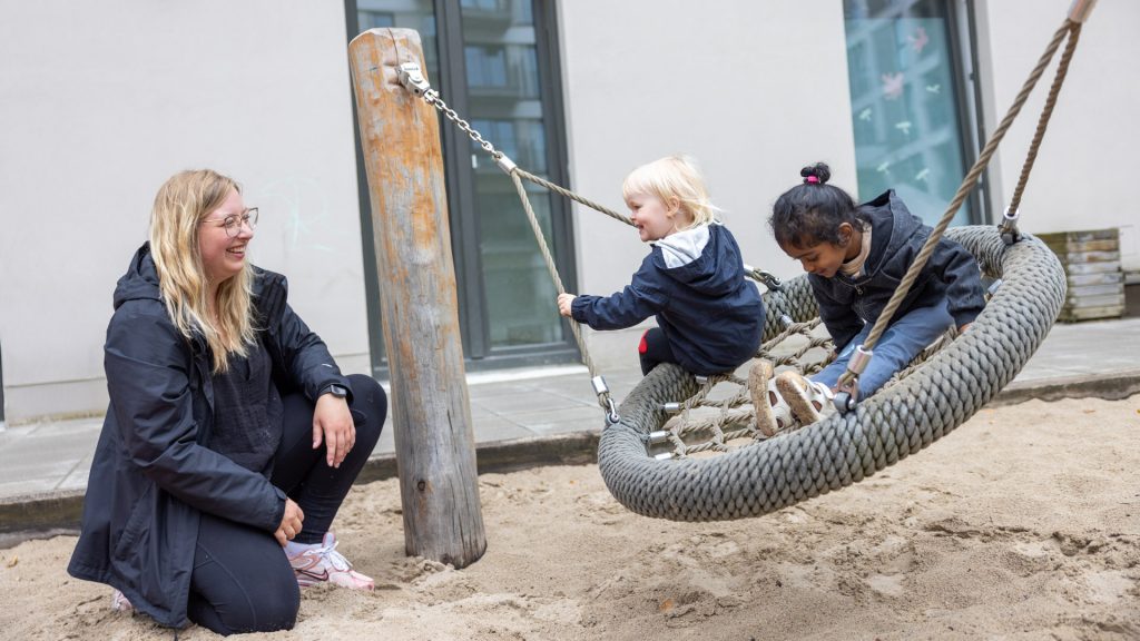 Eine Erzieherin spielt mit Kindern im Sandkasten